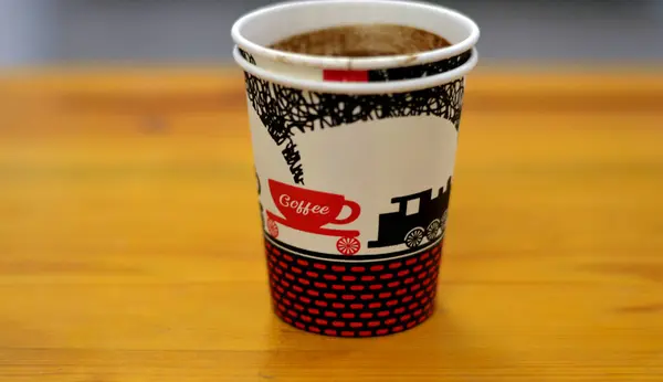 A drunk cup of Turkish coffee in a disposable drinking foam cup isolated on a wooden background, with text of coffee, cup and a train figure, Foam cups are insulated with no heat transfer