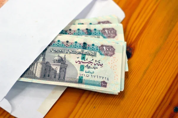 Stack of Egyptian currency of 100 EGP LE 2023 one hundred Egyptian pound bills, spending, giving and using money concept, paying and buying using banknotes with Sultan Hassan mosque and the Sphinx