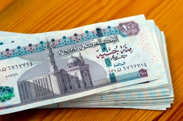 Stack of Egyptian currency of 100 EGP LE 2023 one hundred Egyptian pound bills, spending, giving and using money concept, paying and buying using banknotes with Sultan Hassan mosque and the Sphinx