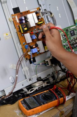 Kahire, Mısır, 3 Ekim 2023: Dijital çokölçer kullanan bir teknisyen mühendisi, LCD TV televizyonunun ana güç devresi, kablolar, transformatörler, direniş, IC, yoğunlaştırıcılar, LG 'nin ana kartının onarımı