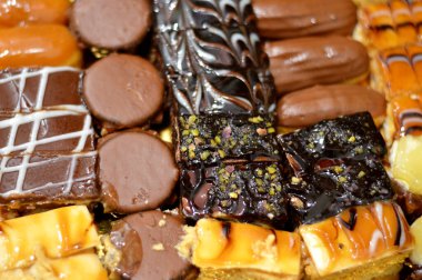 Çeşitli malzemelerle doldurulmuş çeşitli küçük kapak parçaları, kahverengi ve beyaz çikolatalı süngerimsi pasta, karamel, reçel, taze meyve ananas parçaları, seçici odaklı.