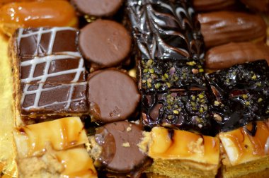 Çeşitli malzemelerle doldurulmuş çeşitli küçük kapak parçaları, kahverengi ve beyaz çikolatalı süngerimsi pasta, karamel, reçel, taze meyve ananas parçaları, seçici odaklı.