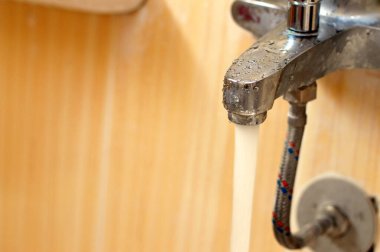 Bir musluktan akan su, banyo ya da mutfaktaki su akışını kontrol etmek için kullanılan bir musluk çeşmesi. Su tasarrufu, sızıntı, su kesintisi, fiksasyon, bakım konsepti.