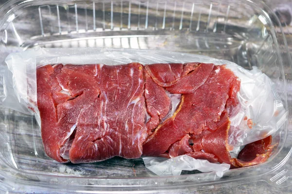 Thin slices of beef pastrami, made from beef brisket, raw meat is brined, partially dried, seasoned with herbs and spices, then smoked and steamed, like corned beef, originating from Romania