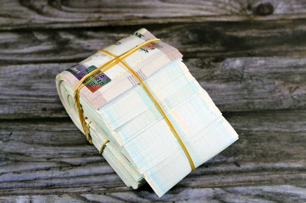 Folded Egyptian money isolated on wooden background, 200 LE 100 EGP LE, two hundred  and one hundred Egyptian pounds cash money bills folded up with rubber bands, exchange rate of Egyptian currency