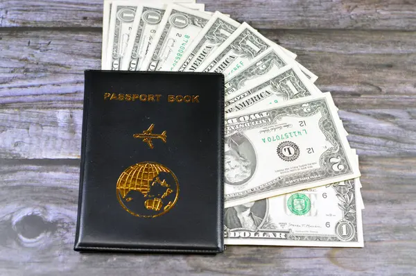 Black passport book with a plane and the globe earth on its cover, travel and tourism concept, universal passport book, American USD United States of America cash money banknotes of dollars