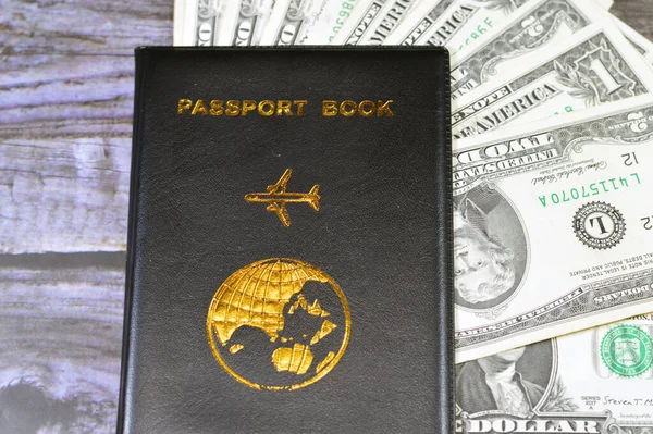 Black passport book with a plane and the globe earth on its cover, travel and tourism concept, universal passport book, American USD United States of America cash money banknotes of dollars