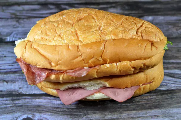 Sandwiches of roast beef slices and Salami in a long bun bread with lettuce and mayonnaise, roasted slices of beef meat as a filling of bun and Salami with melted cheese, selective focus