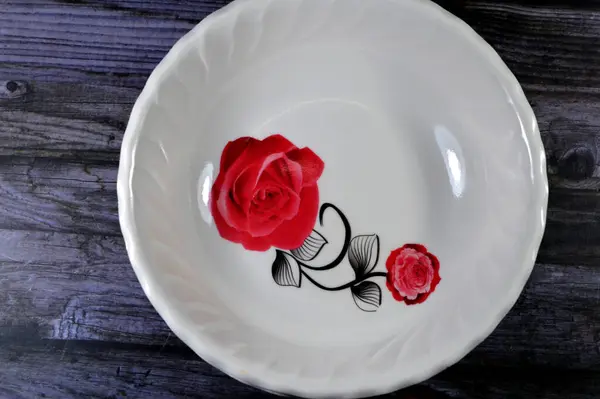 盛食物用的空食物盘 盘子上有一朵红玫瑰花的图片 厨房用具和食物概念 塑料深盘 选择焦点 — 图库照片