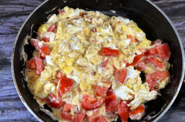 Yumurtalarla çırpılmış domatesler, çırpılmış, çırpılmış ya da çırpılmış yumurtalar, tuzlu, tereyağlı, yağlı ve karabiberli, dilimlenmiş taze domates parçaları ile nazikçe ısıtılırken.