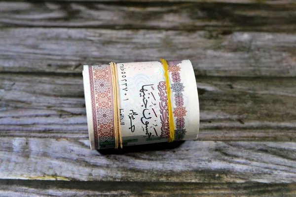 Egypt money roll pounds isolated on wood background, 50 LE fifty Egyptian pounds cash money bills rolled up with rubber bands with a image of Abu Hurayba Mosque, temple of Edfu and winged scarab