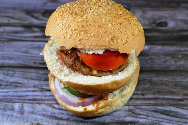 spicy fried beef burger cooked in a boiling shallow oil with slices of  tomatoes, onions, bell peppers in burger bun topped with sesame seeds, Fast food, Junk food concept, beef meat burger sandwich
