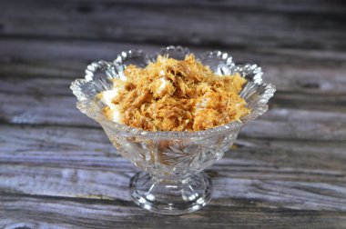 Mısır 'daki tatlı Koshary tarifinin üstüne sütlü puding, krem şanti, kızarmış Konafa ve filo fileto ile birlikte başka tatlar ve dolgu malzemelerinden yapılmış bisküvi kremalı sos.