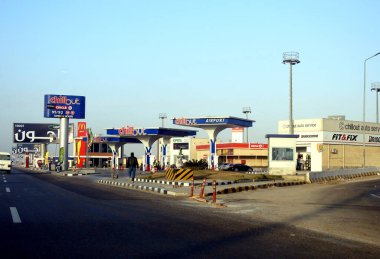 Kahire, Mısır, 23 Aralık 2023: Gündüz serinletici havaalanı benzin ve petrol istasyonu, Kahire havaalanı yakınlarında K mağazaları, McDonald 's ve B daireleri olan bir benzin istasyonu. İstasyonun içindeki teknisyen