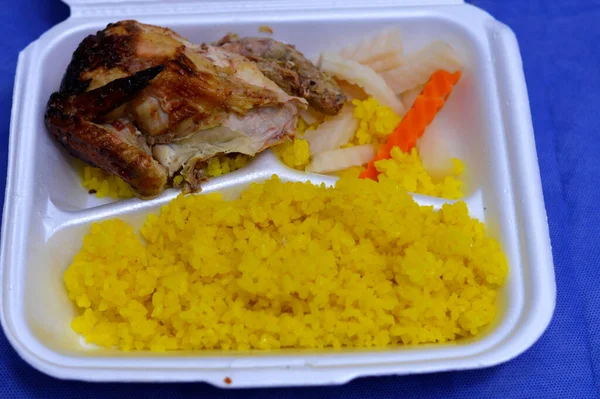 Yellow rice cooked on hot steam, grilled chicken breast with bones and Eastern pickles, marinated carrot slices, turnip pieces, yellow rice with a quarter of chicken cooked on a grill, selective focus