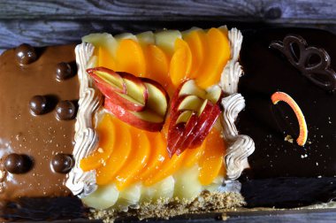 Kutlamalar için üç farklı parçadan oluşan doğum günü pastası süngerimsi kremalı pasta, fındıklı çikolata, koyu çikolata, karamel, çırpılmış vanilyalı krema, ananas, elma, şeftali ve fındık dilimleri