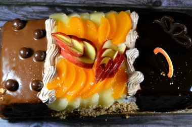 Kutlamalar için üç farklı parçadan oluşan doğum günü pastası süngerimsi kremalı pasta, fındıklı çikolata, koyu çikolata, karamel, çırpılmış vanilyalı krema, ananas, elma, şeftali ve fındık dilimleri