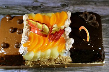 Kutlamalar için üç farklı parçadan oluşan doğum günü pastası süngerimsi kremalı pasta, fındıklı çikolata, koyu çikolata, karamel, çırpılmış vanilyalı krema, ananas, elma, şeftali ve fındık dilimleri