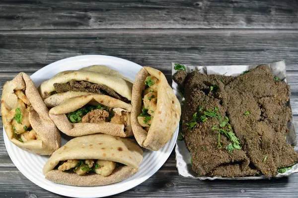 A plate of fried beef liver slices and fried shrimps, beef brain, beef liver slices deep fried in oil and served with parsley in a traditional Egyptian flat bread with wheat bran and flour pitta bread