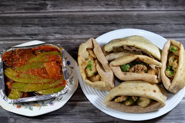Fried and pickled aubergine and green peppers fried shrimps, beef brain, beef liver slices deep fried in oil and served with parsley in a traditional Egyptian flat bread with wheat bran and flour