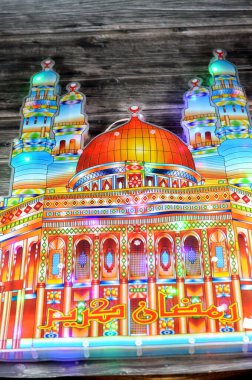 Arapça metnin (Ramazan Kareem veya Cömert Ramazan), minareleri ve kubbesi olan ve dünyadaki Müslümanlar için oruç ayı süslemeleri olan cami şekilli, elektrikli renkli ışıklar üzerine çevirisi