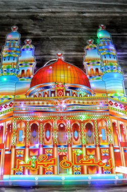 Arapça metnin (Ramazan Kareem veya Cömert Ramazan), minareleri ve kubbesi olan ve dünyadaki Müslümanlar için oruç ayı süslemeleri olan cami şekilli, elektrikli renkli ışıklar üzerine çevirisi