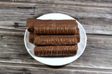 Karamel ve çikolatayla kaplı bisküvi, çikolatalı karamel, lezzetli fıstık ezmesi, tatlı karamel ve yumuşak sütlü çikolatayla kaplanmış kremalı bir merkez.