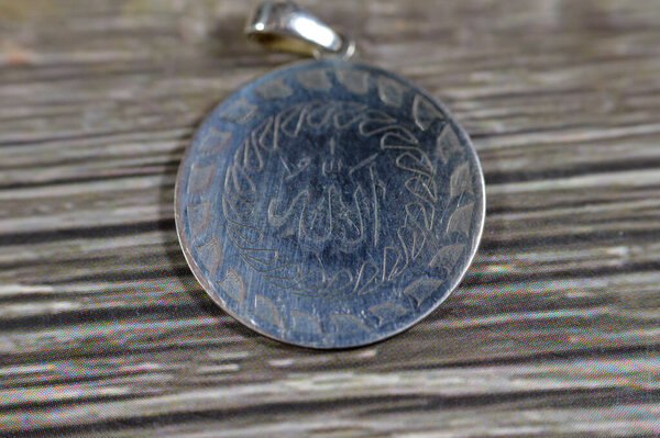 Перевод арабского текста (Аллах, Бог), имя Бога на серебряном кулоне, серебро является химическим элементом Ag, найденный в земной коре в чистой, свободной стихийной форме, ценится как драгоценный металл