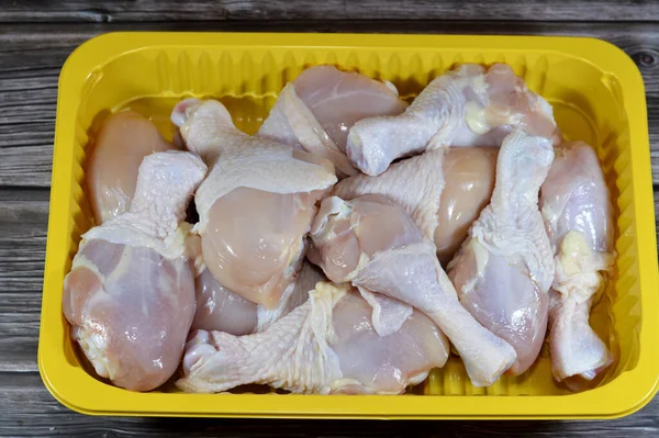 Fresh raw chicken legs drumsticks hindquarter with skin and bones that is ready for baking, grilling, barbecuing, frying or boiling, selective focus of white meat of chicken legs in yellow plate
