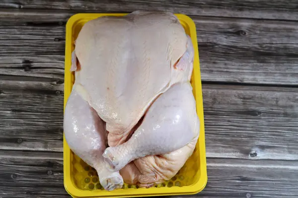 Fresh raw chicken with skin and bones, the whole chicken with breasts, legs, thighs, chicken meat that is ready for baking, grilling, barbecuing, frying or boiling, chicken white meat, selective focus