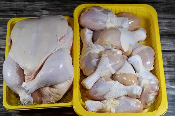 uncooked fresh raw chicken legs drumsticks and thighs hindquarter leg quarters with skin and bones and Fresh raw chicken with skin and bones, the whole chicken with breasts, legs, thighs, chicken meat