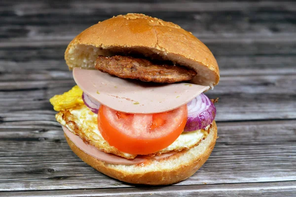 spicy fried beef burger cooked in a boiling shallow oil with slices of  tomatoes, onions, luncheon in burger bun topped with sesame seeds, Fast food, Junk food concept, beef meat burger sandwich