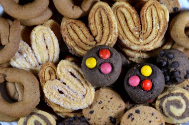 Çeşitli fırında kurabiyeler ve tarçınlı bisküviler, sert, düz ve çıtır çıtır yuvarlak bisküviler, çikolatalı tereyağlı kurabiyeler ve palmier, feuille de palmier 'in kısaltması, Fransız kurabiyeleri.