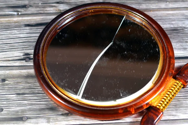Broken hand mirror, cracked, crushed damaged mirror glass, a mirror is an object that reflects an image, also called a looking glass, Mirrors reverse the direction of the image in equal opposite angle