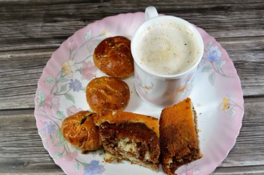 Kremalı köpüklü kapuçino, geleneksel olarak süt köpüğüyle hazırlanmış espresso bazlı kahve içeceği, kaplan mermer sünger keki, tarihli ve sütlü geleneksel Arap kurabiyeleri.