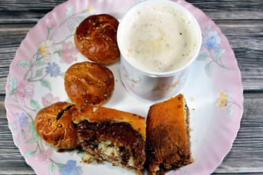 Kremalı köpüklü kapuçino, geleneksel olarak süt köpüğüyle hazırlanmış espresso bazlı kahve içeceği, kaplan mermer sünger keki, tarihli ve sütlü geleneksel Arap kurabiyeleri.