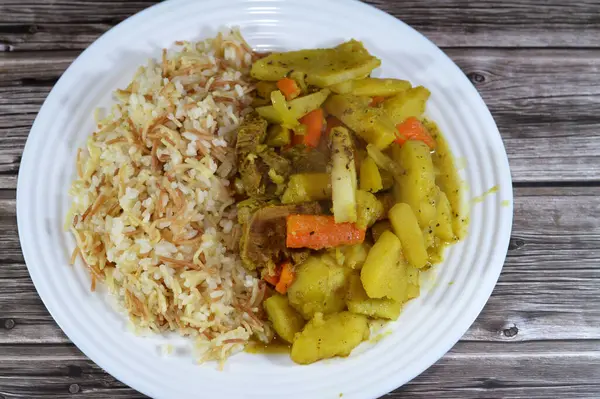 white rice with vermicelli cooked on hot steam, slices of potatoes, carrot, zucchini, onion and tomato with beef meat pieces cooked in the oven, Egyptian Arabic Chicken and vermicelli rice cuisine