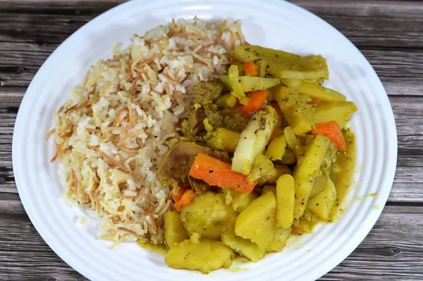 white rice with vermicelli cooked on hot steam, slices of potatoes, carrot, zucchini, onion and tomato with beef meat pieces cooked in the oven, Egyptian Arabic Chicken and vermicelli rice cuisine