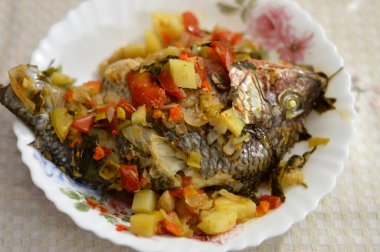 Fırında pişmiş tilapia balığı Oreochromis niloticus domates, patates, havuç, kereviz, soğan, baharat, kimyon, karabiber ve tuz karışımı fırında pişirilmiş, servis edilmeye hazır, seçici odaklanma