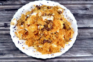 Mısır 'daki tatlı Koshary tarifinin üstüne sütlü puding, krem şanti, kızarmış Konafa ve filo ile birlikte diğer tatlar ve dolgulardan yapılmış çikolata ezmesi sosu.