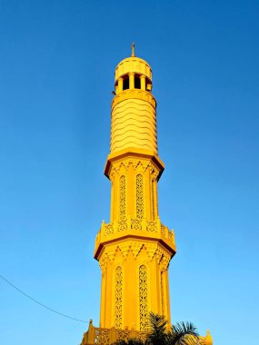 Mavi gökyüzüne, minareye veya kuleye karşı bir caminin altın süslemesine sahip yüksek bir minare, cennet, İslam dini ve mimari konsepti, bir cami direği, seçici odak noktası