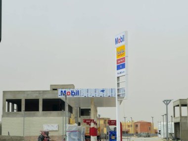 Kahire, Mısır, 10 Mayıs 2024: Mobil doğalgaz, inşaat halindeki petrol istasyonu, Mobil ExxonMobil şirketinin küresel petrol endüstrisi, Mobil1 hizmet merkezi ve içinde kaçak olarak çalışan benzin istasyonu