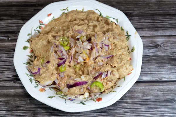 stock image Mashed fava beans mixed with oil, sesame tahini, cumin, spices, slices of chili pepper and onion, traditional popular Egyptian fava bean done the Alexandrian way of Alexandria city of Egypt