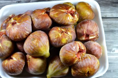 A plate of figs parchment fruit isolated on wooden background, fig is the edible fruit of Ficus carica, a species of small tree in the flowering plant family Moraceae, selective focus