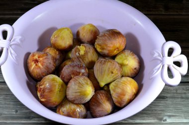 A plate of figs parchment fruit isolated on wooden background, fig is the edible fruit of Ficus carica, a species of small tree in the flowering plant family Moraceae, selective focus