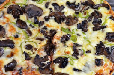 Siyah mantar dilimli mantar pizzası, zeytin, sebze, mozarella peyniri, zeytin yağı ve taze otlar, yüksek kenarlı yuvarlak, fırında pişirilmiş, seçici odaklı