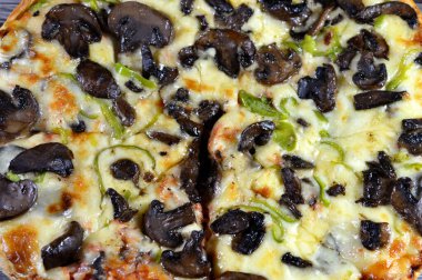 Siyah mantar dilimli mantar pizzası, zeytin, sebze, mozarella peyniri, zeytin yağı ve taze otlar, yüksek kenarlı yuvarlak, fırında pişirilmiş, seçici odaklı