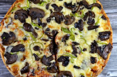 Siyah mantar dilimli mantar pizzası, zeytin, sebze, mozarella peyniri, zeytin yağı ve taze otlar, yüksek kenarlı yuvarlak, fırında pişirilmiş, seçici odaklı