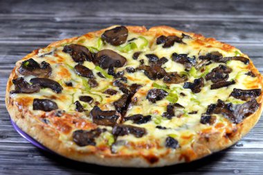 Siyah mantar dilimli mantar pizzası, zeytin, sebze, mozarella peyniri, zeytin yağı ve taze otlar, yüksek kenarlı yuvarlak, fırında pişirilmiş, seçici odaklı