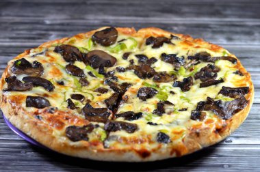 Siyah mantar dilimli mantar pizzası, zeytin, sebze, mozarella peyniri, zeytin yağı ve taze otlar, yüksek kenarlı yuvarlak, fırında pişirilmiş, seçici odaklı